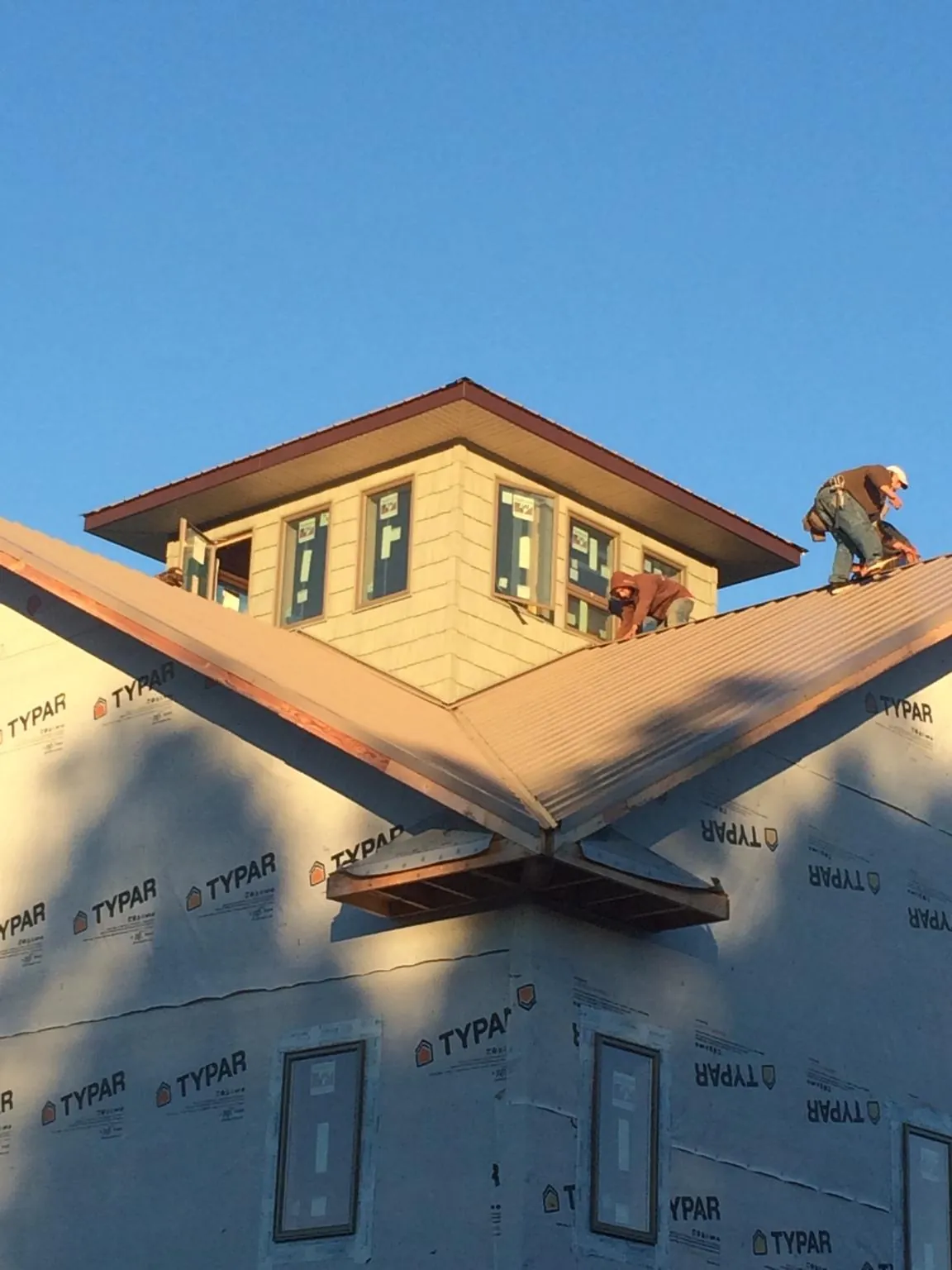Roofers working around a rooftop cupola on a new metal roof at sunset — Roof Waterproofing in Parsons by Roofing Brothers